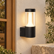 Aplique exterior cilíndrico negro mate con difusor opal, vista en ambiente instalado