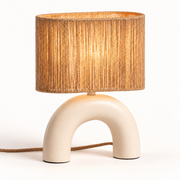 Lámpara de mesa beige de cerámica con base en arco y pantalla de cuerda, luz encendida