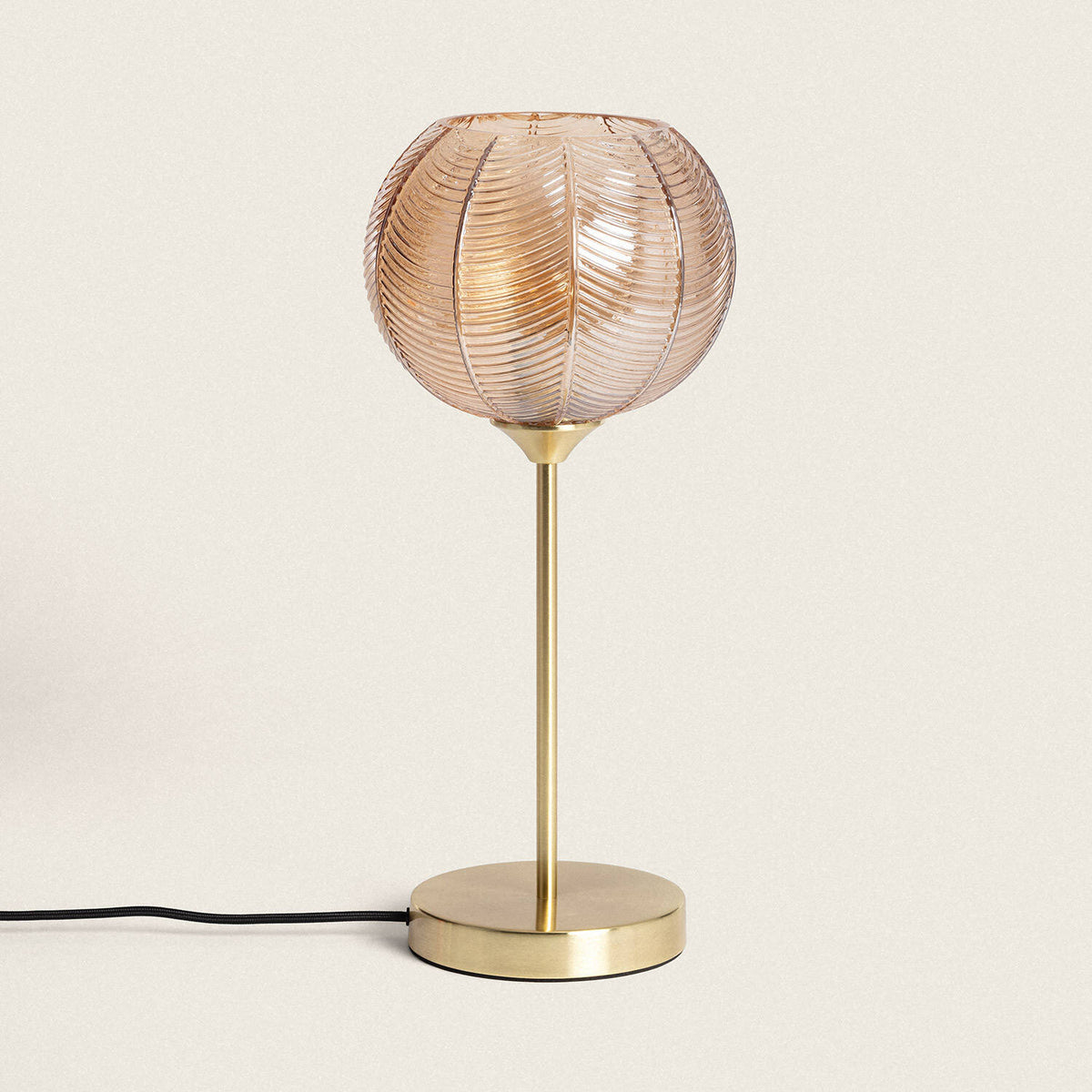 Lámpara de mesa dorada con tulipa de cristal ámbar E27. Vista real con la luz apagada, color y acabado originales