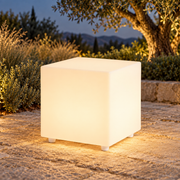 Cubo decorativo LED LedsCome de 30 cm con luz cálida en un jardín al atardecer. Representación ambiental.