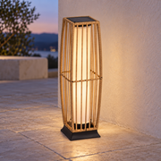 Farol solar de pie en acabado natural encendido sobre el suelo de una terraza clara