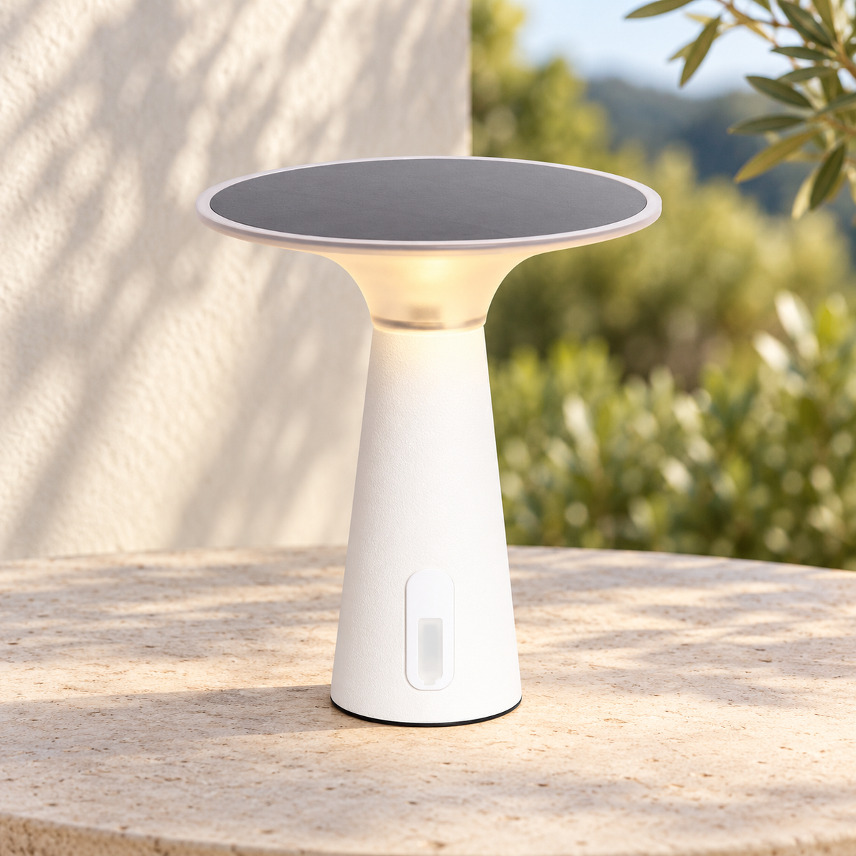 Lámpara portátil blanca con disco solar encendida sobre una mesa de terraza