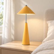 Lámpara de mesa amarilla de cuero y metal encendida en una mesita de dormitorio claro