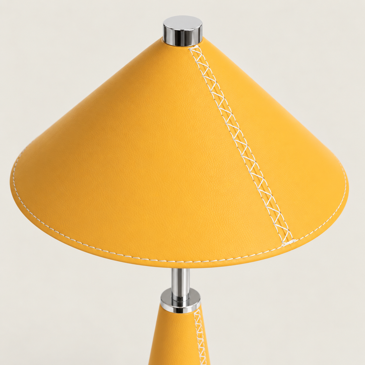 Detalle de la costura blanca en la pantalla de cuero amarillo y el fuste metálico