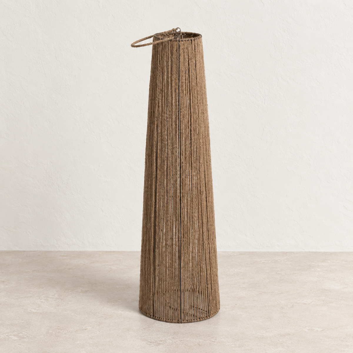 Farol alto de cuerda de cáñamo apagado sobre suelo de piedra clara