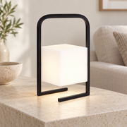 Farol negro con difusor cúbico encendido sobre una mesa clara