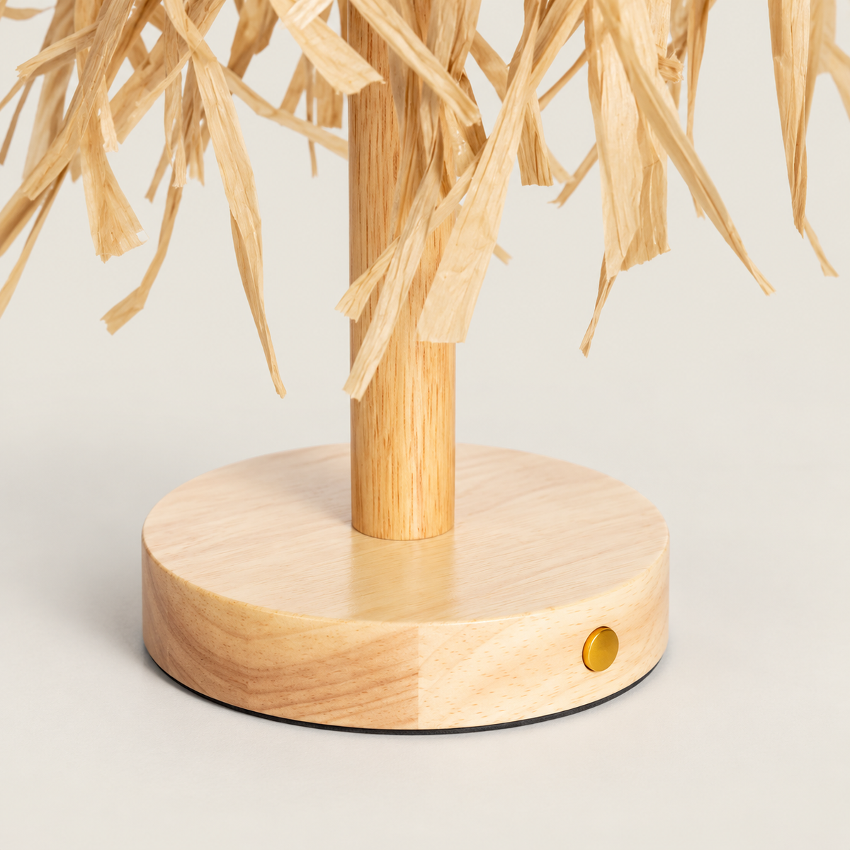 Detalle de la base de madera, el botón lateral y los flecos naturales de la lámpara