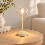 Mini lámpara de mesa beige con pantalla transparente encendida en un ambiente claro