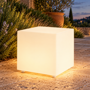 Cubo decorativo LED LedsCome de 38 cm con luz cálida en un jardín al atardecer. Representación ambiental.