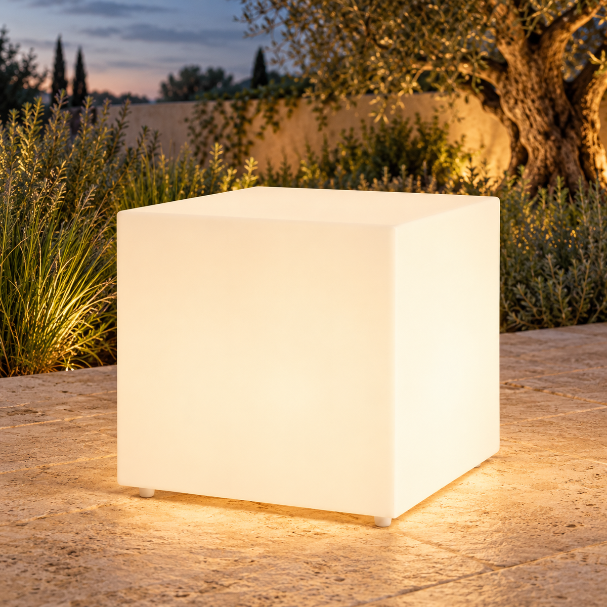 Cubo decorativo LED LedsCome de 50 cm con luz cálida en un jardín al atardecer. Representación ambiental.