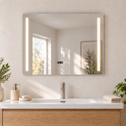 Espejo horizontal de 80 × 60 cm con bandas LED cálidas, reloj y controles sobre un lavabo