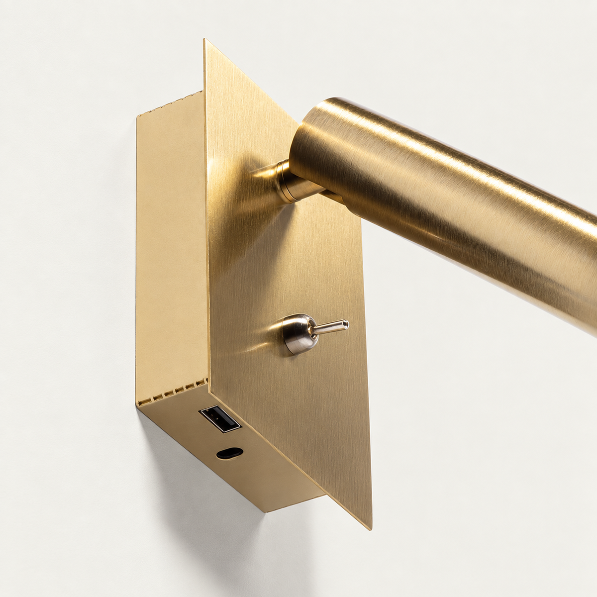 Detalle inferior del aplique dorado con un puerto USB-A, orificio de tornillo e interruptor frontal