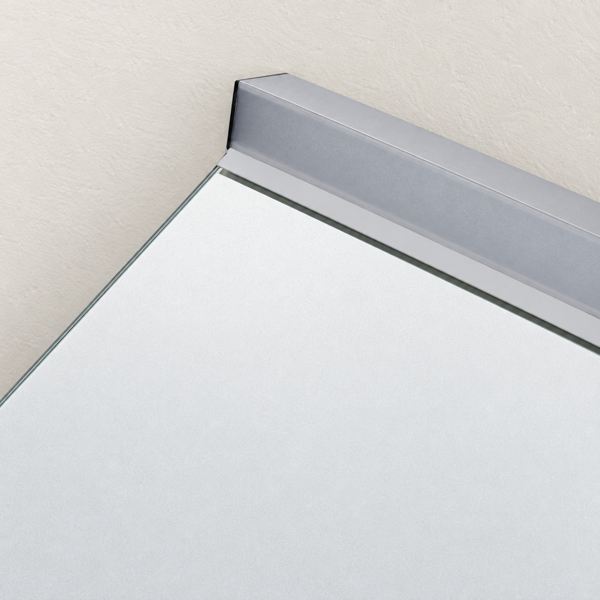 Detalle del perfil gris de la barra de luz superior y el canto del espejo